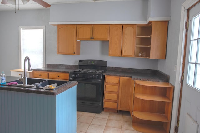 kitchen featuring light tile patterned floors, open shelves, dark countertops, black range with gas stovetop, and a sink