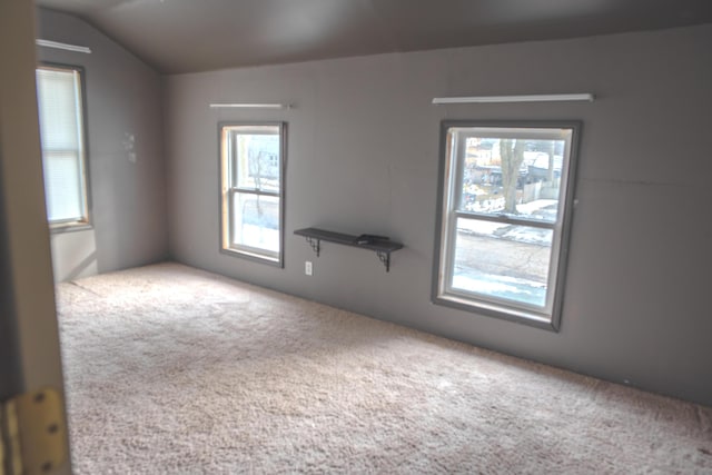 spare room with light carpet and vaulted ceiling