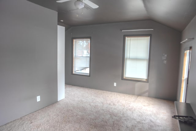 carpeted empty room with lofted ceiling and a ceiling fan