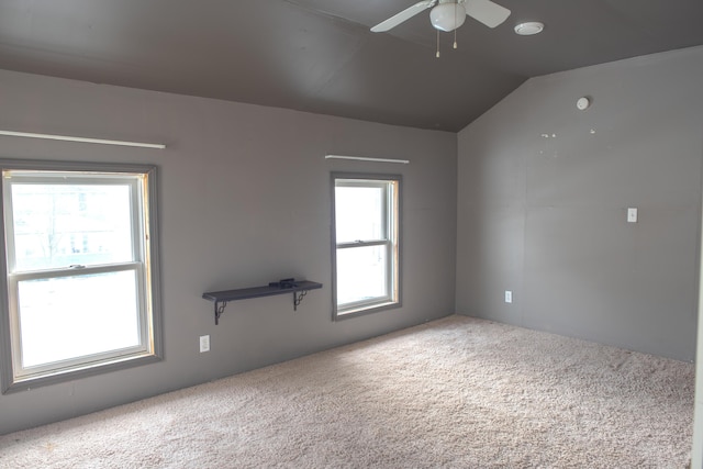 carpeted spare room with lofted ceiling and a ceiling fan