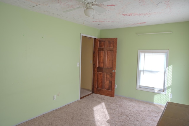 unfurnished room with a textured ceiling, a ceiling fan, and light colored carpet