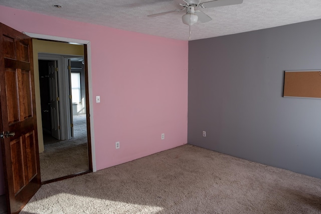 spare room with light carpet, ceiling fan, and a textured ceiling