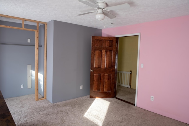 unfurnished bedroom with light colored carpet, ceiling fan, and a textured ceiling