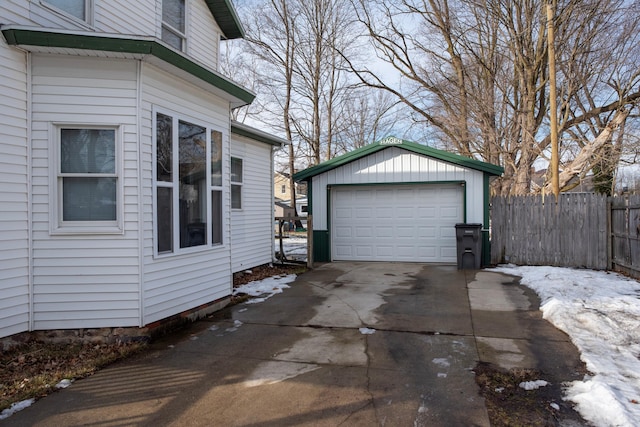 view of side of home featuring a garage, concrete driveway, an outbuilding, and fence