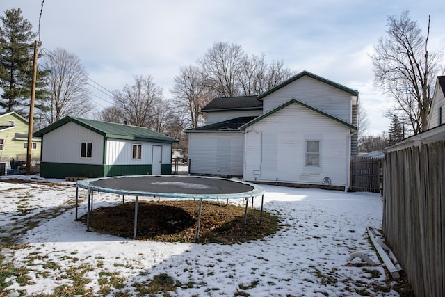 snow covered property with a trampoline and fence