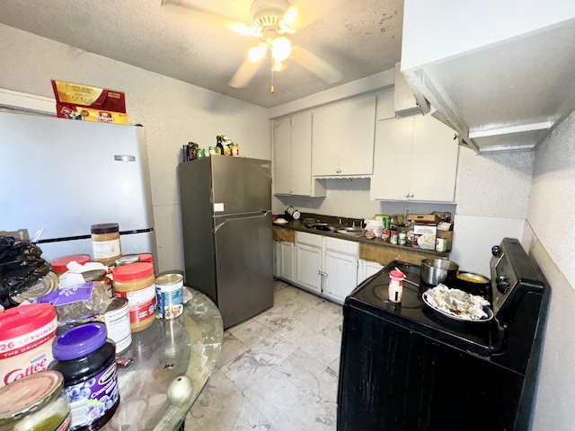 kitchen featuring freestanding refrigerator, white cabinets, a sink, and electric range