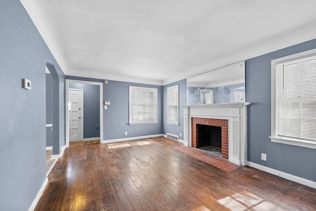 unfurnished living room featuring arched walkways, a fireplace, wood-type flooring, visible vents, and baseboards