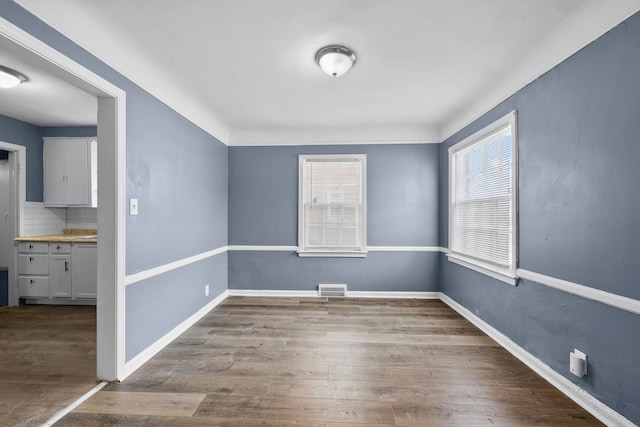 spare room featuring wood finished floors, visible vents, and baseboards