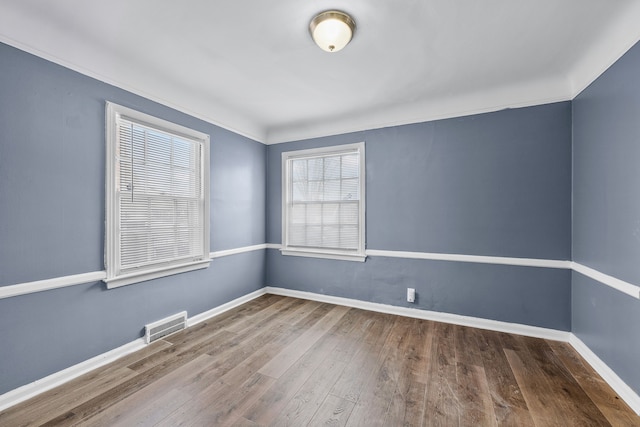 unfurnished room with baseboards, visible vents, and wood finished floors