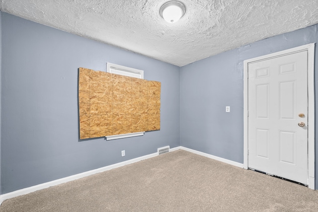 unfurnished room with carpet flooring, visible vents, baseboards, and a textured ceiling