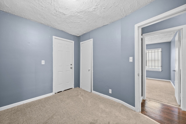 carpeted spare room featuring baseboards and a textured ceiling