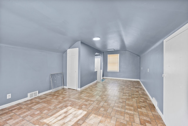 bonus room featuring lofted ceiling, visible vents, arched walkways, and baseboards