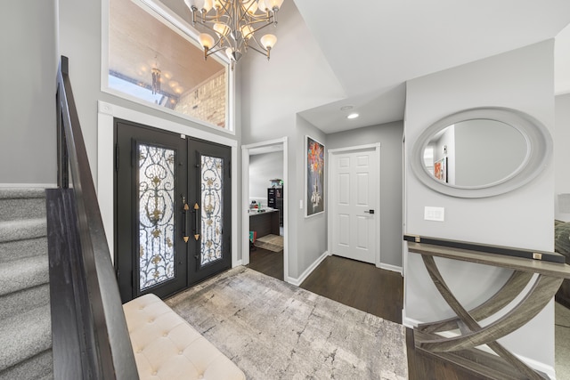 foyer with french doors, wood finished floors, a chandelier, baseboards, and stairs