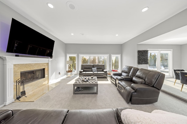 carpeted living room featuring baseboards, a premium fireplace, and recessed lighting