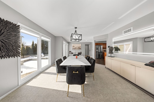 dining area with light carpet, visible vents, and a notable chandelier