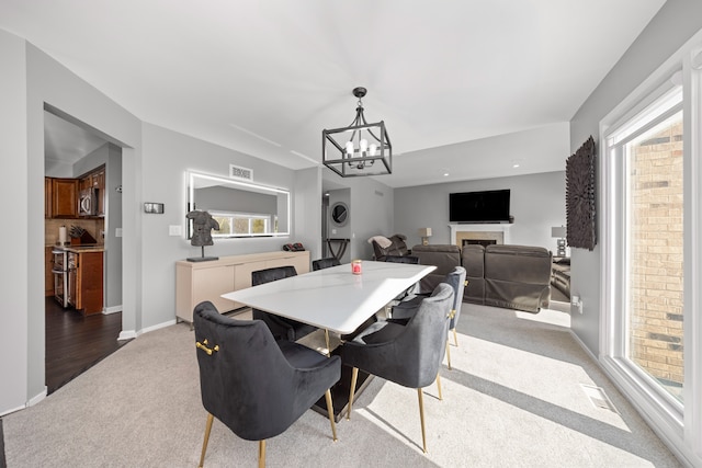 dining room with stacked washer / drying machine, light carpet, plenty of natural light, and a notable chandelier