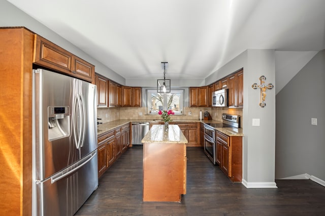 kitchen with stainless steel appliances, light stone counters, a center island, and decorative backsplash