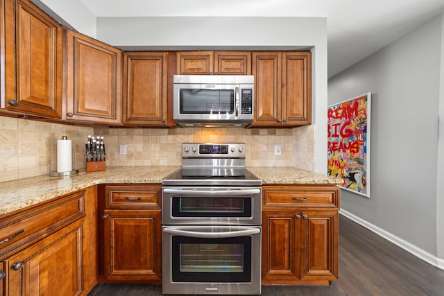 kitchen featuring brown cabinets, tasteful backsplash, baseboards, and stainless steel appliances