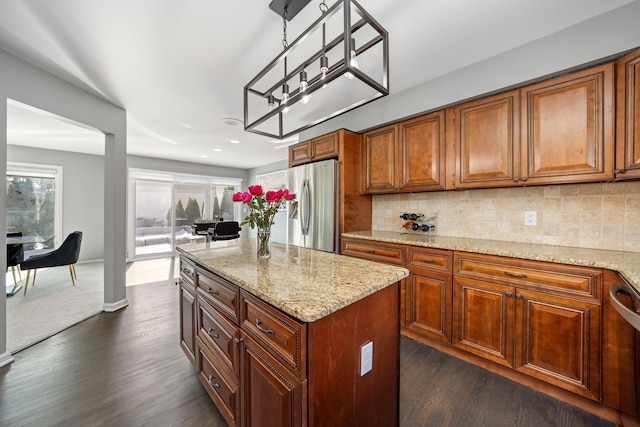 kitchen featuring stainless steel appliances, tasteful backsplash, light stone countertops, and brown cabinets