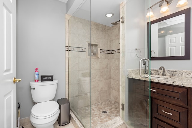 bathroom with tiled shower, vanity, and toilet