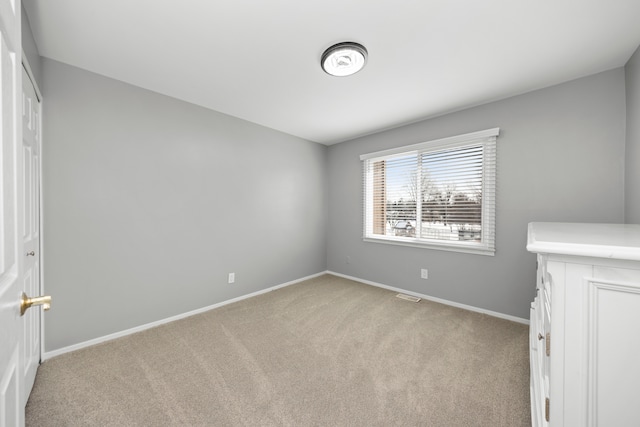 unfurnished bedroom featuring light colored carpet, visible vents, and baseboards