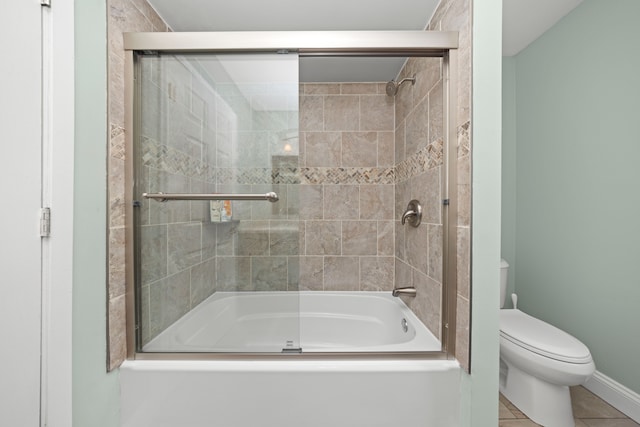 bathroom with baseboards, shower / bath combination with glass door, toilet, and tile patterned floors