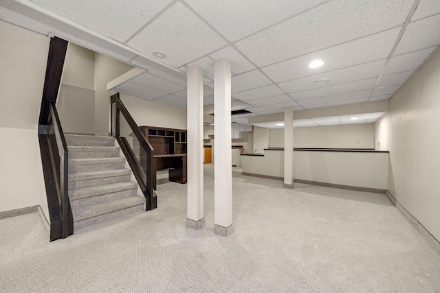 finished basement with a paneled ceiling, carpet flooring, baseboards, and stairs