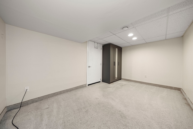 empty room with a paneled ceiling, recessed lighting, baseboards, and light colored carpet