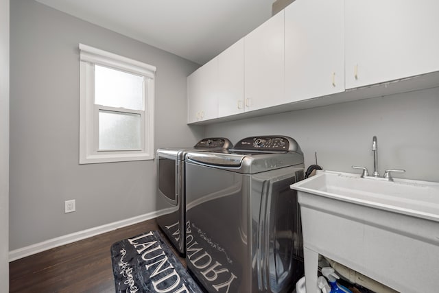 clothes washing area featuring dark wood finished floors, cabinet space, a sink, washer and dryer, and baseboards