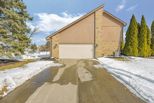 exterior space with a garage, central AC, and brick siding