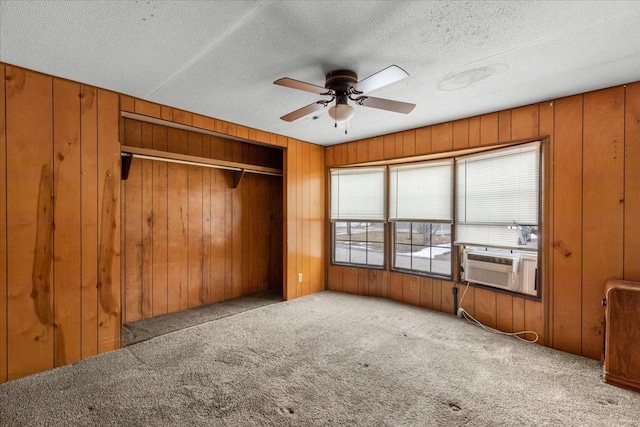 carpeted empty room with wooden walls, cooling unit, a textured ceiling, and a ceiling fan