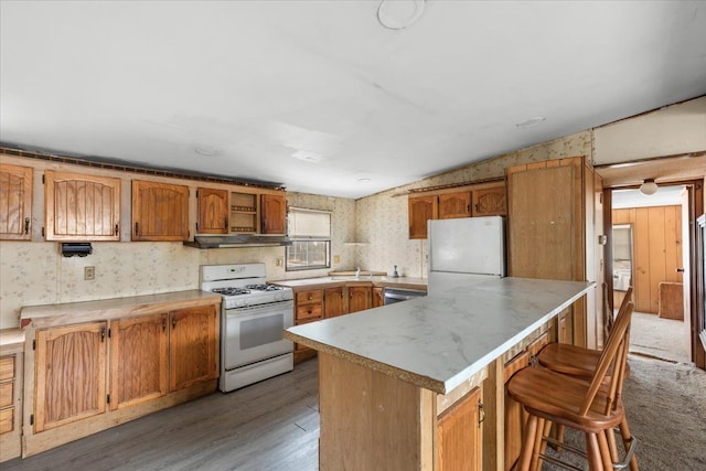 kitchen with lofted ceiling, white appliances, wood finished floors, and wallpapered walls