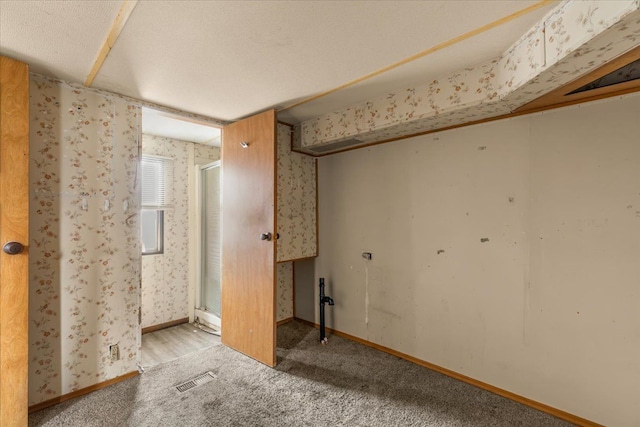 interior space with carpet floors, visible vents, baseboards, and wallpapered walls