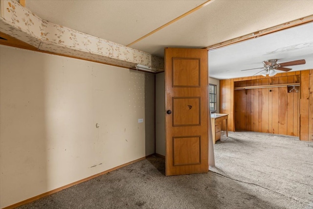 interior space featuring wood walls, ceiling fan, and baseboards