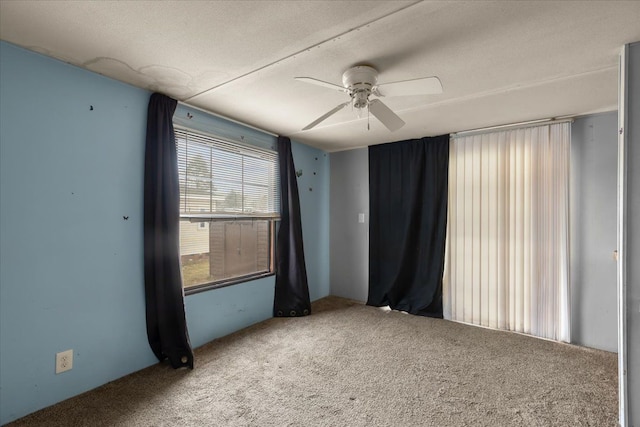 empty room with ceiling fan, a textured ceiling, and carpet flooring