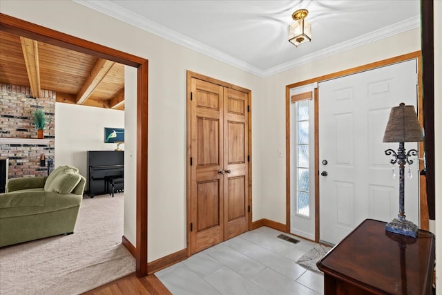 entrance foyer featuring visible vents, beam ceiling, a fireplace, crown molding, and baseboards