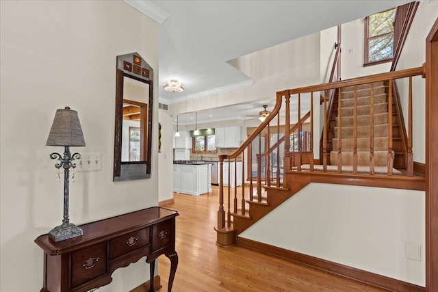 foyer entrance with light wood-type flooring, visible vents, ornamental molding, and stairs