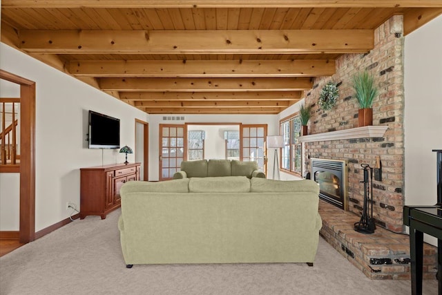 living area with baseboards, beam ceiling, wood ceiling, a brick fireplace, and light colored carpet