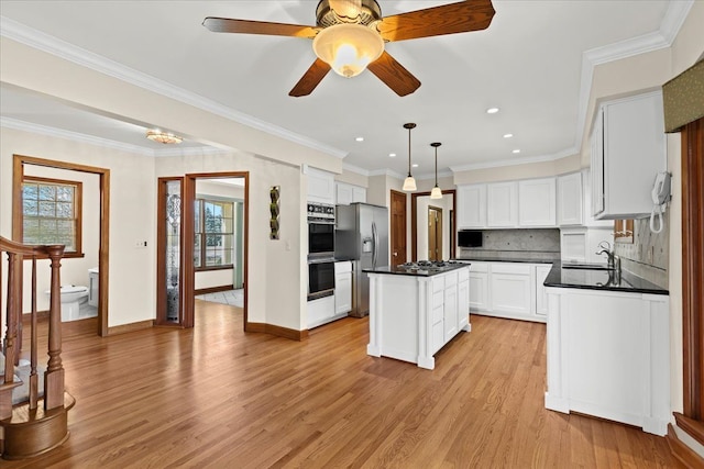 kitchen featuring dark countertops, a kitchen island, light wood-style flooring, stainless steel fridge with ice dispenser, and double oven