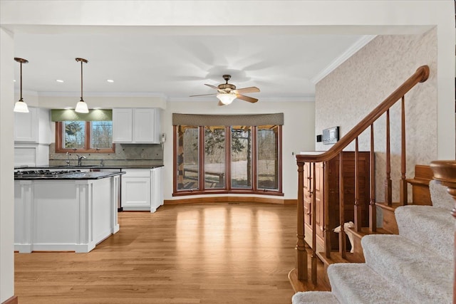 kitchen featuring ornamental molding, dark countertops, open floor plan, white cabinetry, and light wood-style floors