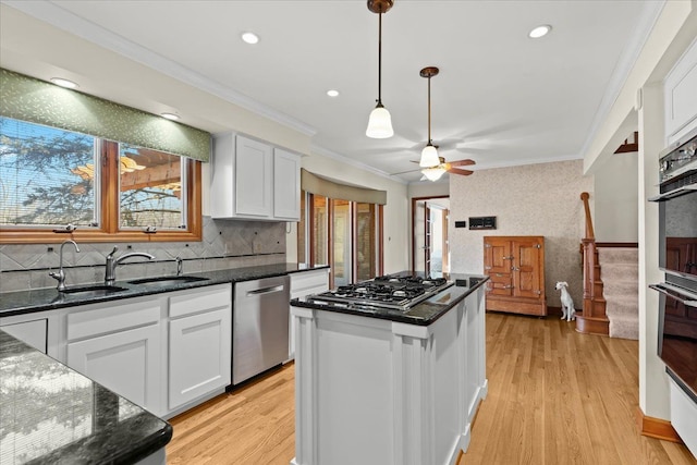 kitchen with ornamental molding, a sink, a center island, white cabinetry, and appliances with stainless steel finishes