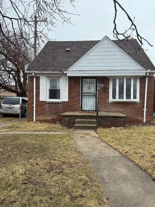 bungalow-style house featuring brick siding, roof with shingles, and a front yard