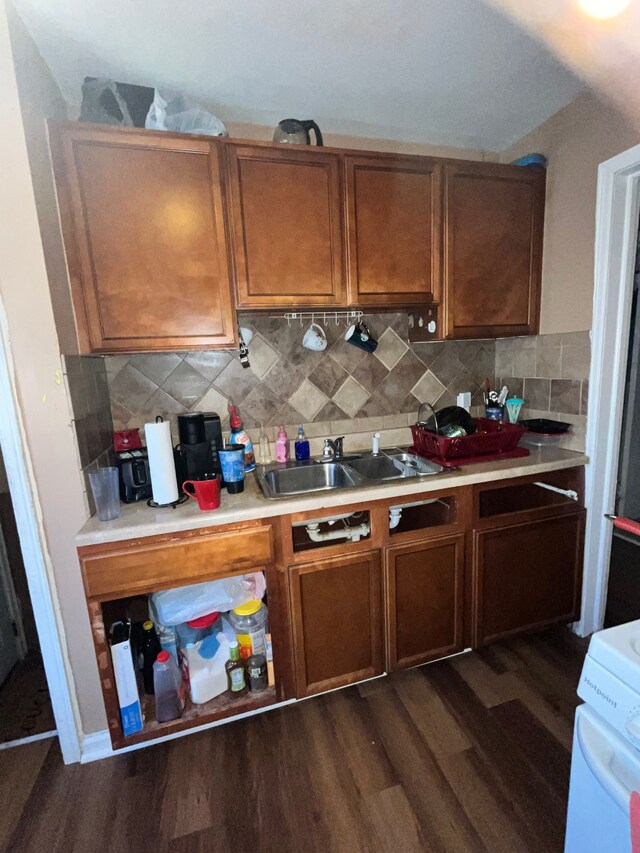kitchen featuring decorative backsplash, range, a sink, light countertops, and dark wood-style floors
