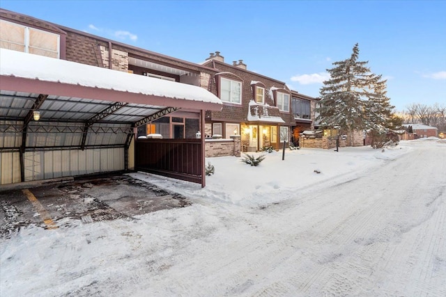 snow covered rear of property featuring brick siding