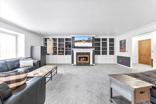 living area with carpet floors, a premium fireplace, built in features, and crown molding