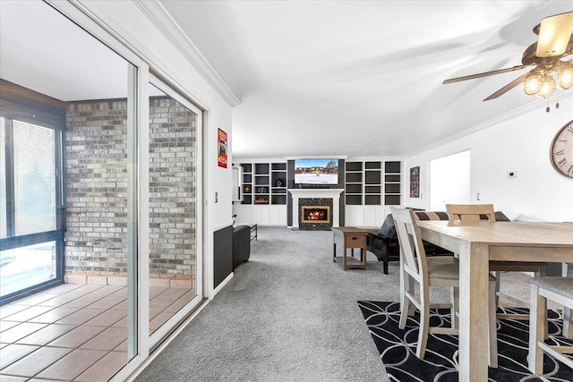 carpeted dining space with ceiling fan, a fireplace, and crown molding