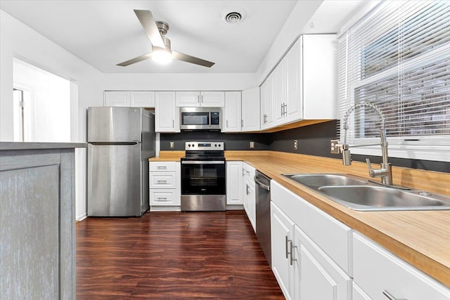 kitchen with visible vents, dark wood-style floors, appliances with stainless steel finishes, white cabinetry, and a sink