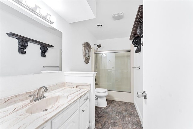 full bathroom with visible vents, toilet, shower / bath combination with glass door, stone finish floor, and vanity