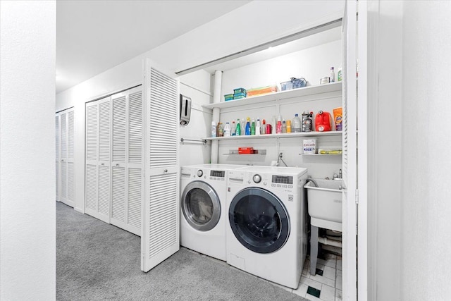 washroom featuring laundry area, washer and clothes dryer, and a sink