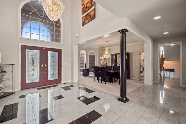 foyer entrance with a chandelier, a towering ceiling, decorative columns, and baseboards